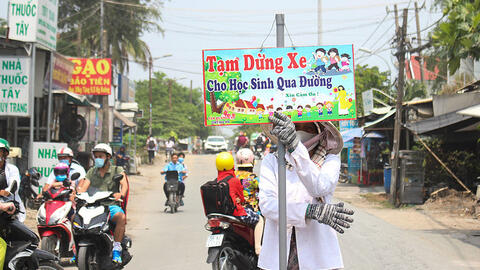 Người phụ nữ hằng ngày cầm biển chặn xe giúp học sinh qua đường
