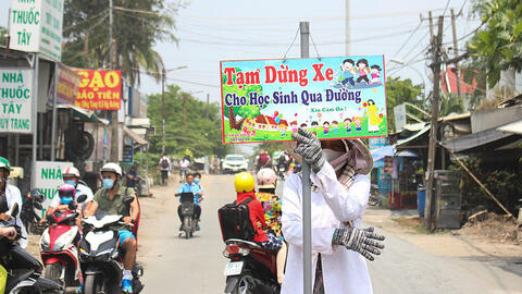 Người phụ nữ hằng ngày cầm biển chặn xe giúp học sinh qua đường