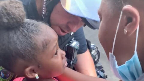 Cảnh sát ôm trấn an bé gái da màu giữa biểu tình