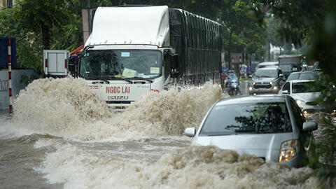 Người dân Hà Nội bì bõm sau cơn mưa lớn, có nơi ngập sâu gần hết bánh xe máy