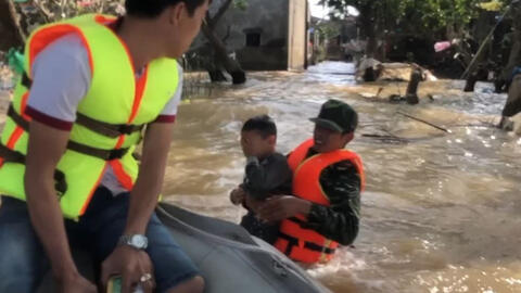 Người đàn ông nhảy xuống dòng nước lũ bế em bé lên nhận hàng cứu trợ