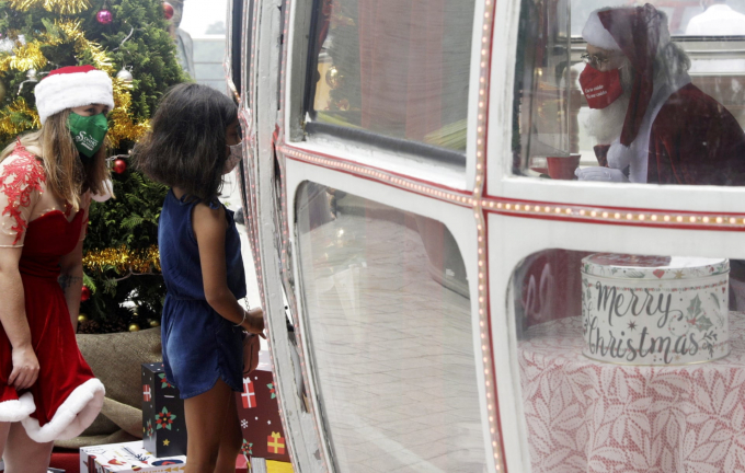 Một bé gái ghé thăm ông già Noel trong một khoang cáp treo cũ gần dãy núi Sugar Loaf tại Rio de Janeiro, Brazil (Ảnh: Ricardo Moraes/Reuters).