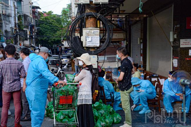 Các lực lượng chức năng mặc đồ bảo hộ làm nhiệm vụ tiếp tế dưới thời tiết oi nóng 38 độ.