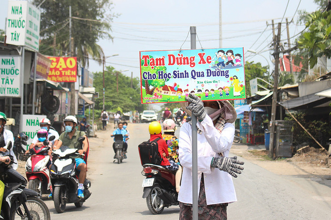   Bà Phượng đứng cầm bảng xin đường cho học sinh di chuyển sang đường trưa ngày 8/4. Ảnh: Diệp Phan.  