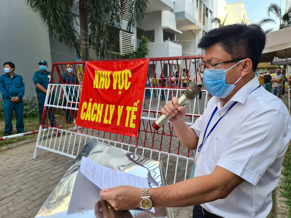 Ông Nguyễn Thanh Tâm - Chủ tịch UBND TP Thuận An (Bình Dương) đọc quyết định tháo dỡ phong tỏa tại một chung cư sau khi hoàn thành cách ly COVID-19 - Ảnh: tuoitre.vn