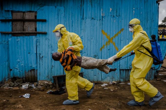 Các nhân viên y tế ở Monrovia, Liberia, mang theo James Dorbor, một đứa trẻ 8 tuổi bị nghi nhiễm virut Ebola, vào một cơ sở điều trị vào tháng 9 năm 2014. Tây Phi đang đối phó với dịch Ebola bùng phát nguy hiểm nhất. Vụ dịch kết thúc vào năm 2016 sau hơn 11.000 ca tử vong. Ảnh: Daniel Berehulak / Thời báo New York / Redux