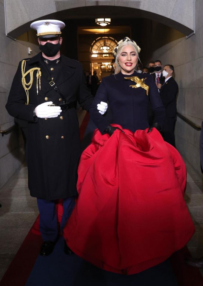   Cũng trong sự kiện này, Lady Gaga tạo nên khoảnh khắc đáng nhớ khi diện váy Haute Couture của Schiaparelli với màu đỏ tượng trưng cho tình yêu nước, cài áo chim bồ câu mang cành ô liu đại diện cho sự hàn gắn, bên trong mặc áo chống đạn.   