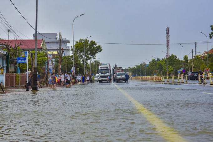 Nhiều phương tiện và người dân vẫn chờ nước tại quốc lộ này rút để đi qua.