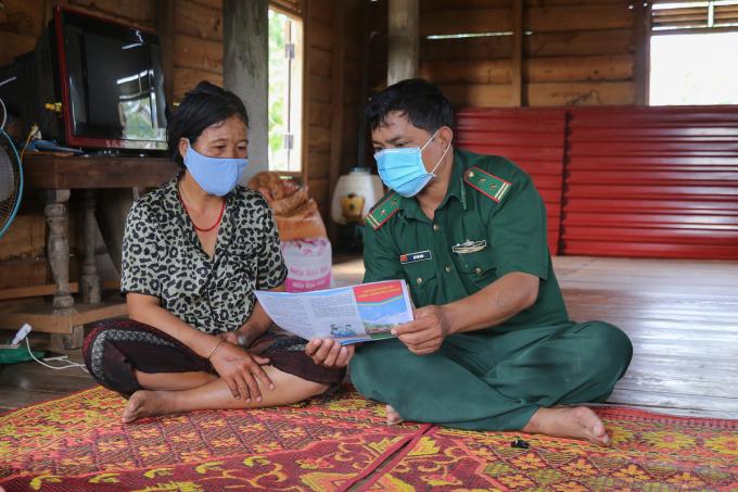 Trong thôn, trung tá Hồ Văn Năm tuyên truyền cho một hộ dân cách phòng chống dịch. 