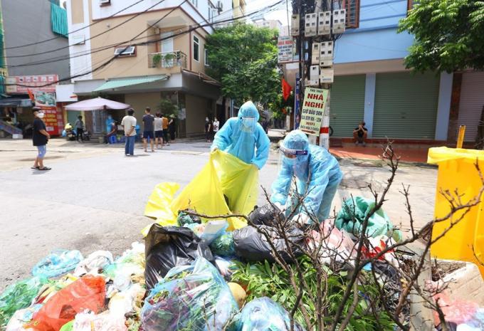 Những công nhân môi trường làm việc trong khu vực phong tỏa luôn phải hết sức chú ý phòng dịch vì có nguy cơ lây nhiễm cao. (Ảnh: Hoàng Hiếu/TTXVN)