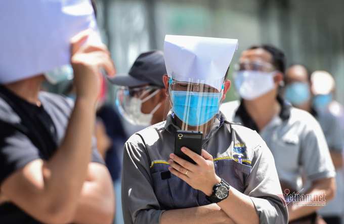 Anh Vương Hữu Huyền làm việc cho một phòng khám cũng rơi vào hoàn cảnh tương tự, anh đứng xếp hàng khá lâu vẫn chưa được vào tiêm. Anh Huyền dùng giấy ghi thông tin để che nắng