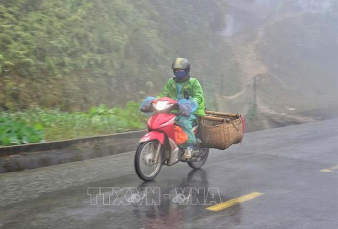   Người dân đi xe máy vận chuyển hàng hóa trong sương sớm, giá lạnh trên đỉnh đèo Pha Đin (Điện Biên). Ảnh: Xuân Tiến-TTXVN   