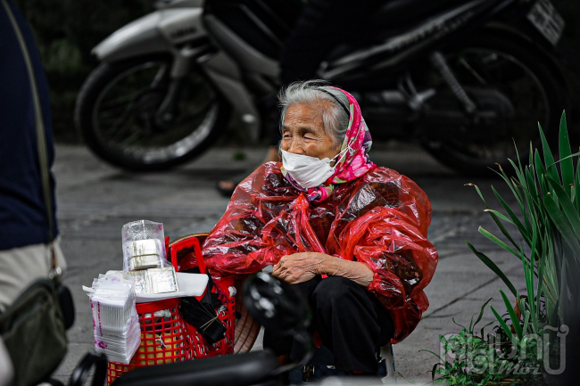 Bà cụ bán hàng rong mặc thêm áo mưa để đỡ lạnh.