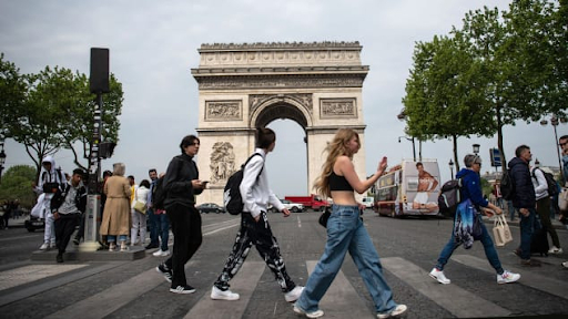   Người đi bộ băng qua đại lộ Champs-Élysées trước tượng đài Khải Hoàn Môn ở Paris ngày 29/04/2022. Pháp ở Cấp độ 3, nguy cơ 