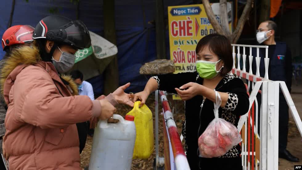 Người dân truyền nhau những can nước và thực phẩm tại một chốt kiểm soát ở Sơn Lôi.