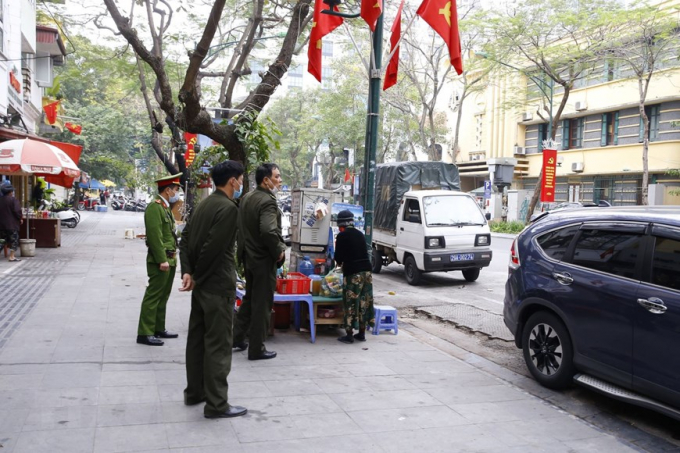 Lực lượng công an phường Cửa Nam ra quân đề nghị các hộ kinh doanh đóng cửa quán ăn đường phố, trà đá, cà phê. Ảnh: Doãn Tuấn/TTXVN