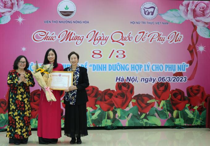 Phó Chủ tịch Thường trực, TS. Phạm Thị Mỵ (bìa trái) và PCT, PGS.TS. Bùi Thị An, Hội NTT Việt Nam (bìa phải) tặng Bằng khen và hoa cho KS. Lê Thị Hương, hội viện của Chi hội có thành tích xuất sắc năm 2022