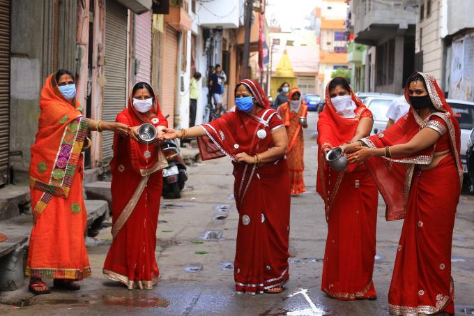 Những phụ nữ đạo Hindu dâng nước cho thần mặt trời trong lúc thực hiện nghi thức của lễ hội Gangaur khi lệnh phong tỏa tại quốc gia này bị áp đặt (Ảnh: Vishal Bhatnagar | NurPhoto | Getty Images).