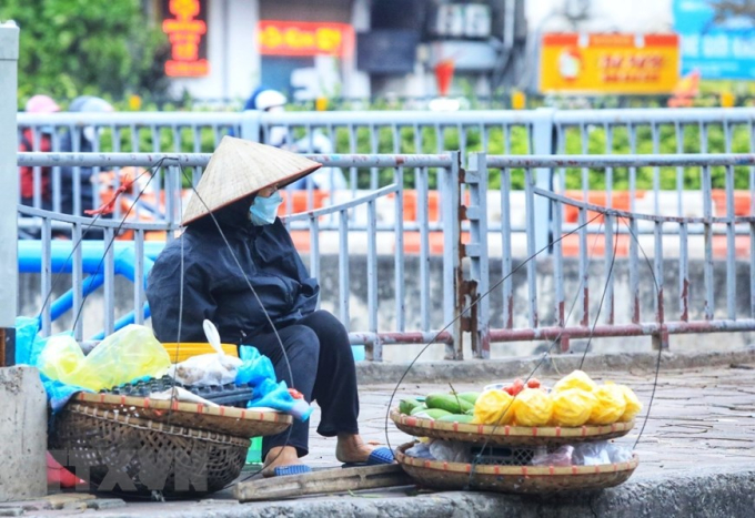 Một người bán hàng rong chờ khách mua trên phố. (Ảnh: Tuấn Anh/TTXVN)