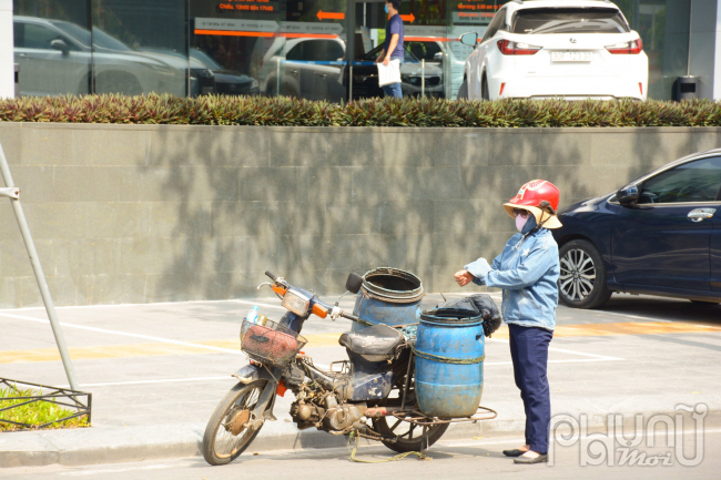 Người phụ nữ tranh thủ thu gom đồ ăn thừa buổi trưa hà nắng gắt.