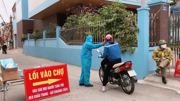   Đo nhiệt độ trước khi vào chợ tại Chí Linh, Hải Dương - Ảnh: ĐỨC TÙY  