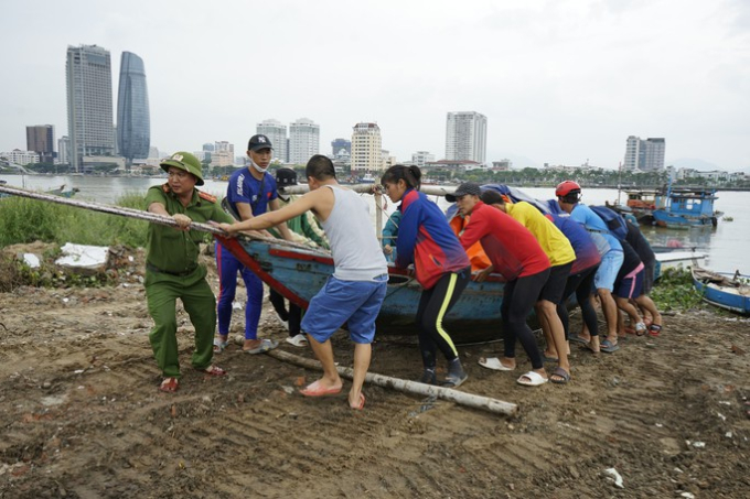   Lực lượng chức năng hỗ trợ người dân đưa tàu thuyền lên tránh bão Ảnh: Quang Luật  