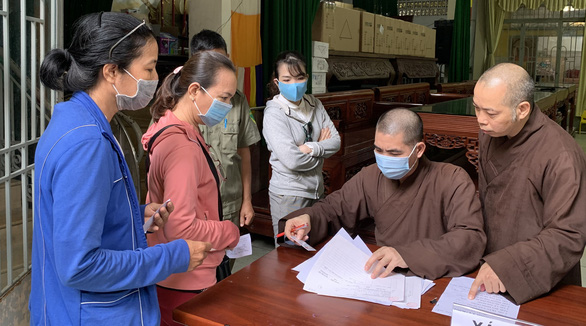   Thượng tọa Thích Quang Thạnh (bìa phải) hướng dẫn thủ tục nhận diện tro cốt, di ảnh cho thân nhân - Ảnh: PHƯƠNG NAM  