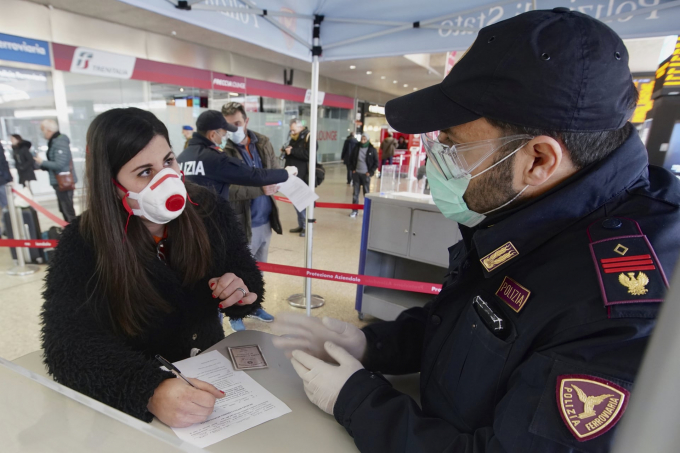 Một người đeo khẩu trang khi điền vào mẫu khai tại trạm xe lửa ở Rome (Ảnh: Andrew Medichini/AP).