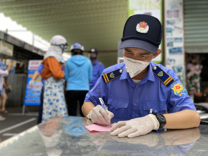   Bảo vệ chợ Cồn điền thông tin vào phiếu giúp người dân trước khi vào chợ.  