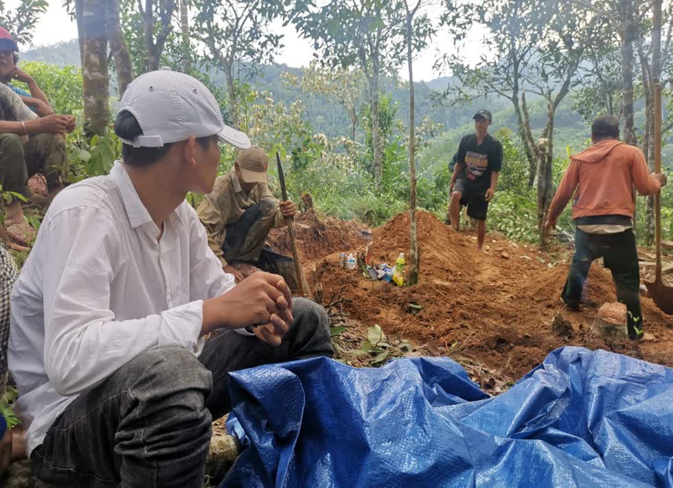 Hồ Văn Trung ngồi bên 2 ngôi mộ mới đắp của cha mẹ là vợ chồng chủ vườn quế, ông Hồ Văn Thành và bà Hồ Thị Đức. Ảnh: Zing