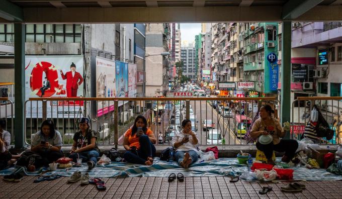 Người giúp việc tụ tập theo dõi thông tin trên cầu đi bộ tại Mong Kok hôm 22/6(Ảnh: Bloomberg)