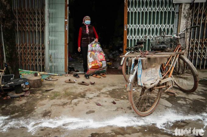 Bà Phạm Thị Trang, một người dân tại thôn Ái Văn, rắc vôi bột khử trùng trước cửa nhà. Từ ngày trong thôn có người bị nhiễm virus corona, bà hạn chế ra đường. Khi đưa hàng cho các hộ gia đình ở các xã khác, các bạn hàng cũng yêu cầu bà Trang đặt hàng ở phía ngoài, họ tự ra lấy, hạn chế tiếp xúc trực tiếp.