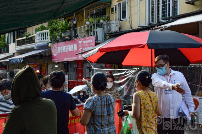 Cán bộ quản lý chợ yêu cầu người dân giãn cách đúng quy định 5k.