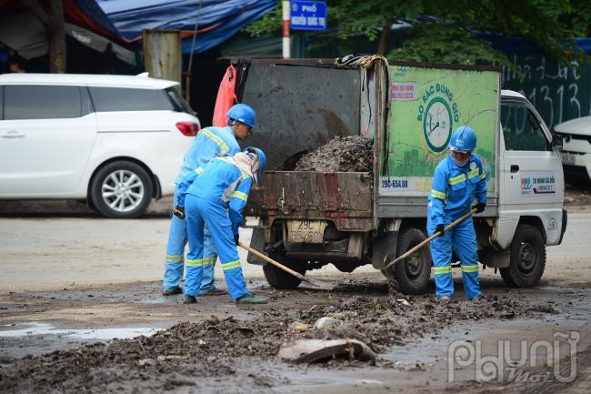 Công nhân đang dọn bùn đất do ngập lắng đọng lại tại phố Nguyễn Quốc Trị.