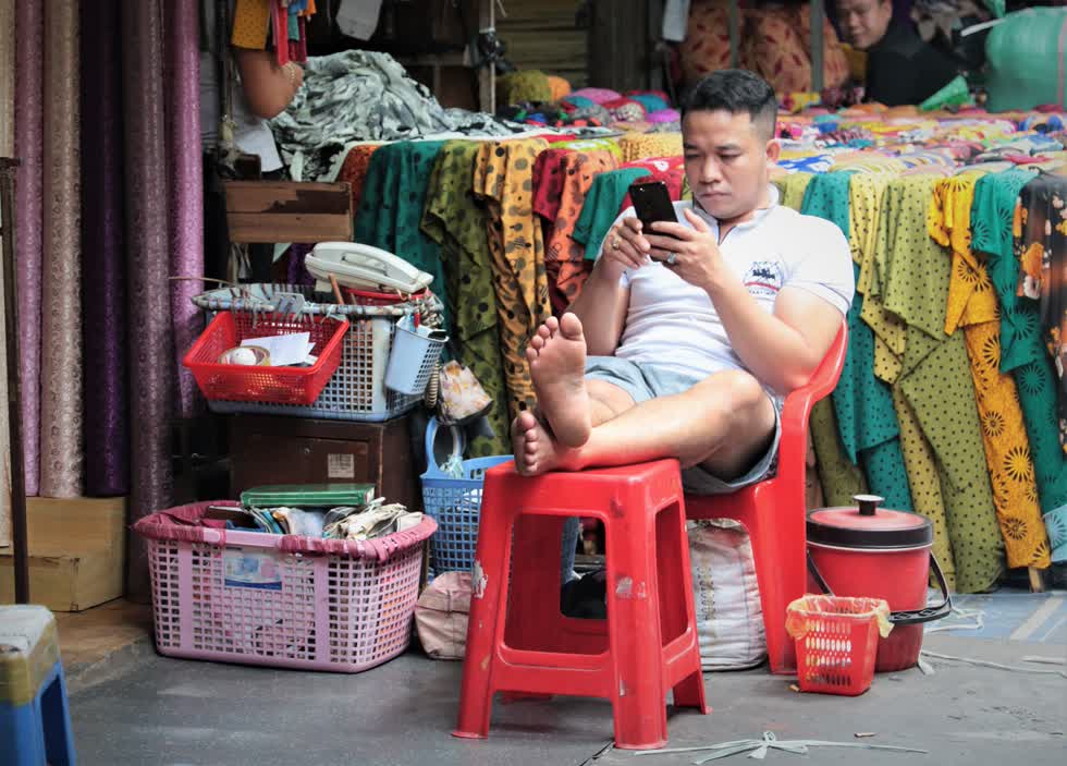 Hình ảnh tiểu thương ngồi bấm điện thoại...