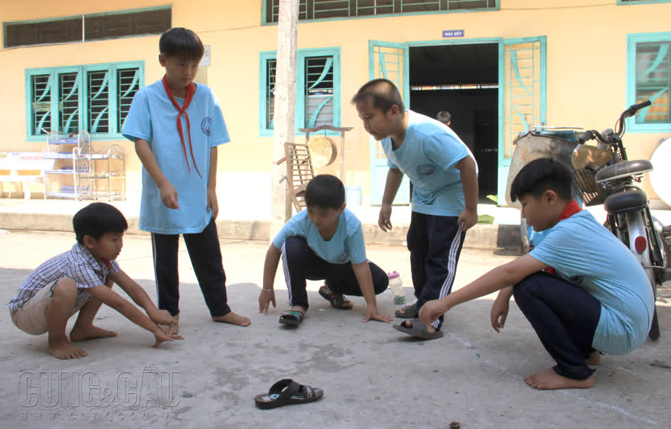 Đám trẻ tiểu học giờ tan lớp, tụ tập chơi bắn bi trước nhà ăn.