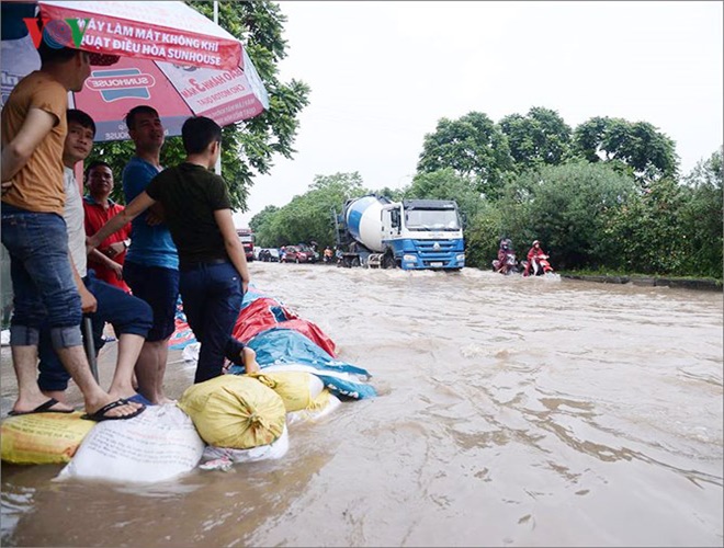 Khu vực Đại lộ Thăng Long chìm trong biển nước, có chỗ ngập sâu đến gần 1m, người dân phải lấy bao cát chắn để tránh nước tràn vào nhà. Nhiều phương tiện giao thông không dám băng qua vì sợ chết máy. (Ảnh: VOV)