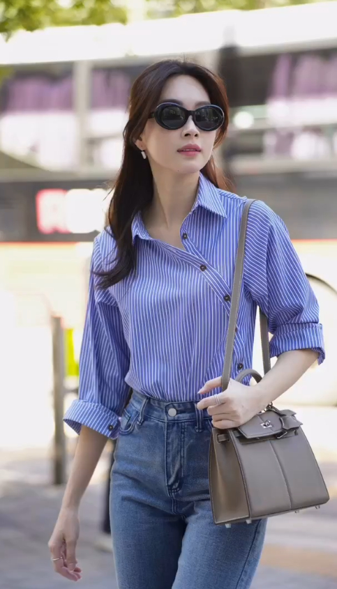 Cô phối áo sơ mi kẻ sọc cùng quần jeans và không quên mix thêm túi xách, mắt kính. 