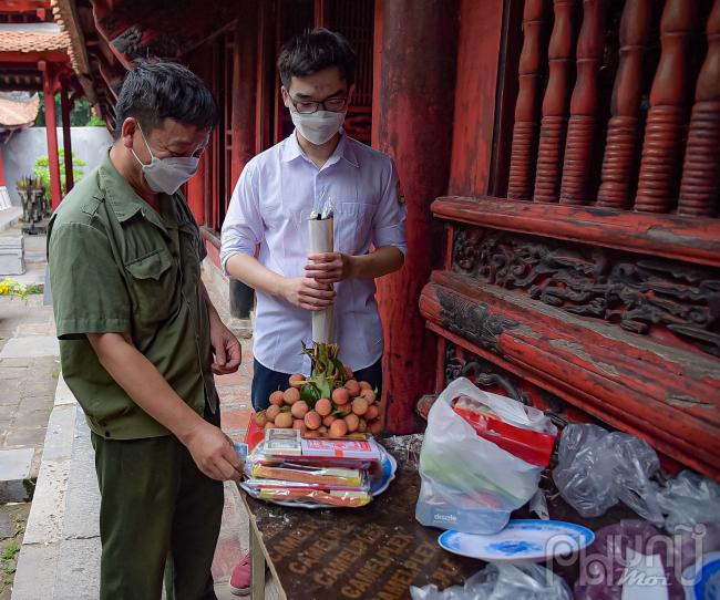 Phụ huynh của em Nguyễn Huy Anh đang sắp lễ vật chia sẻ: Phải cận kề ngày thi tôi mới đưa con đến Văn Miếu. Đây là việc để giúp giải tỏa tâm lý, giúp cháu bình tĩnh, tự tin mang lại kết quả tốt hơn trong kì thi.