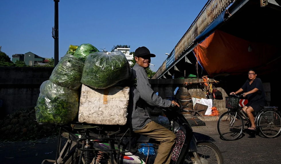 Một người bán hàng vận chuyển rau tại chợ đầu mối ở Hà Nội. Ảnh: AFP